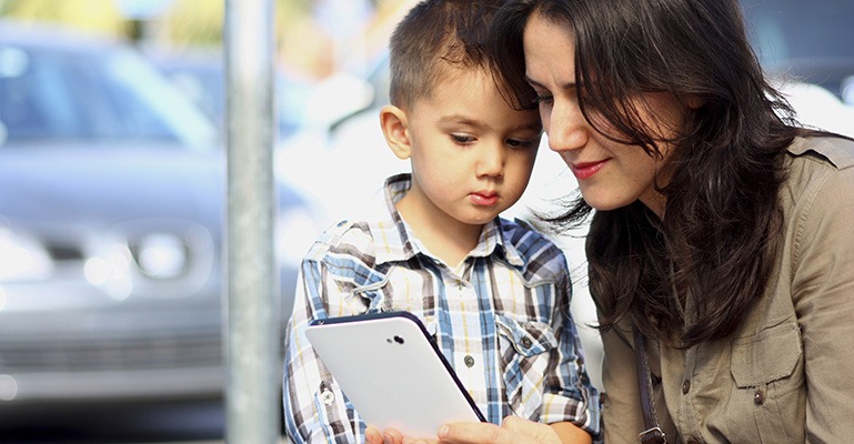 A young mother and her young son look at a tablet together.
