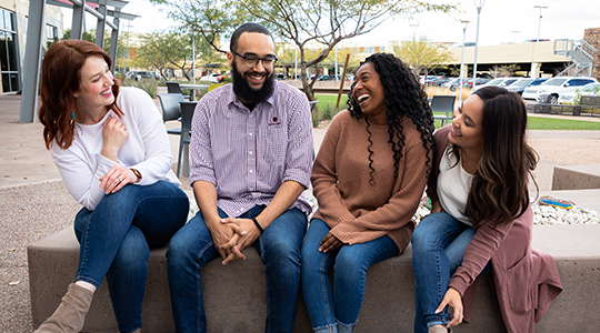 A group of friends sitting outside and laughing.